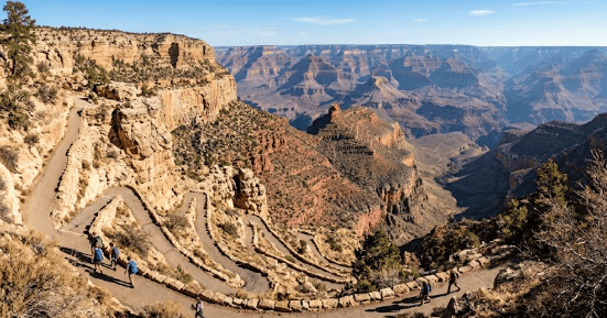 Breathtaking view of the Grand Canyon with winding trail and layered cliffs.